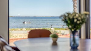 A view of the sea through a window, a boat, and a palm tree. - "Catalina" - 30m from the sea by Interhome (Sjølund)