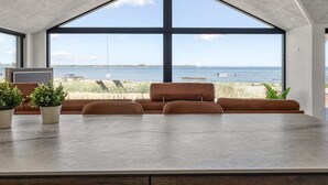 A modern interior with a large window overlooking a beach and sea. - "Catalina" - 30m from the sea by Interhome (Sjølund)
