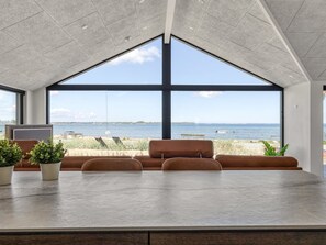 A modern interior with a large window overlooking a beach and sea. - "Catalina" - 30m from the sea by Interhome (Sjølund)
