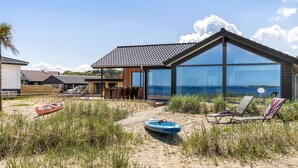 A modern beach house with a large glass facade, a covered patio, and beach chairs. - "Catalina" - 30m from the sea by Interhome (Sjølund)