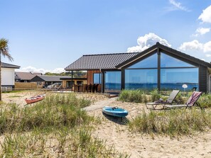 A modern beach house with a large glass facade, a covered patio, and beach chairs. - "Catalina" - 30m from the sea by Interhome (Sjølund)
