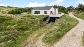 Ein modernes Haus mit Flachdach, überdachter Terrasse und einem Kiesweg, der dorthin f ührt.