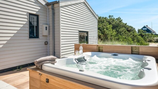 Ein Whirlpool in einer Holzterrasse mit einem Haus im Hintergrund.