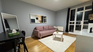 Ett modernt vardagsrum med en soffa, ett soffbord och en matplats med stolar och ett bord.
