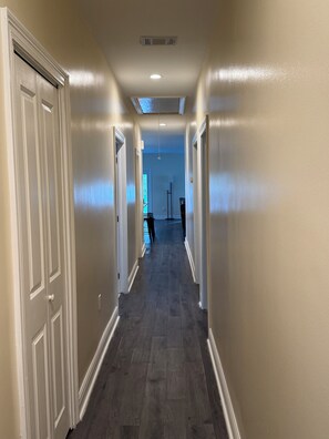 A hallway with a dark wood floor, white walls, and a ceiling vent. - Charming 3-bedroom 2-full bath house with parking in the  Mid-city  New Orleans (New Orleans)