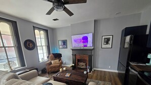 A living room with a sofa, a coffee table, a fireplace, and a television. - Highlands Hideaway - Walk to Bars, Food & Coffee (Louisville)