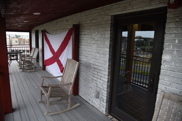 Una terraza de madera con mecedoras y una gran bandera blanca y roja.