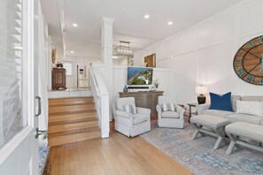 A spacious living room with a large TV, white furniture, and a patterned rug. - The Neptune House 3 bedrooms by the sea (St Simons Island)
