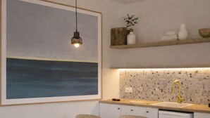 A modern kitchen with a dining area, featuring a wooden table and chairs, a small refrigerator, and a backsplash with speckled tiles. - Casa Pino-private family villa with pool in Corfu, close to beaches/water park (Corfu)