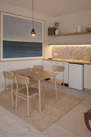 A modern kitchen with a dining area, featuring a wooden table and chairs, a small refrigerator, and a backsplash with speckled tiles. - Casa Pino-private family villa with pool in Corfu, close to beaches/water park (Corfu)