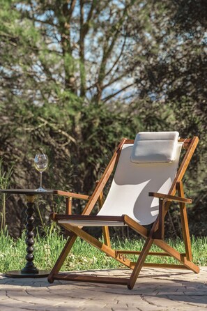 A wooden lounge chair with a white cushion, positioned on a paved area with grass and trees in the background. - Casa Pino-private family villa with pool in Corfu, close to beaches/water park (Corfu)