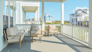 A covered porch with a sofa, chairs, and a table. - Beautiful Second Row Beachside Home - Steps from Sand & Surf (Galveston)