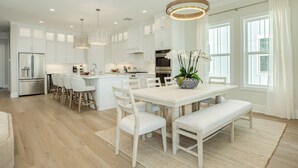 A modern kitchen with white cabinetry, a central island, and pendant lighting. - Beautiful Second Row Beachside Home - Steps from Sand & Surf (Galveston)