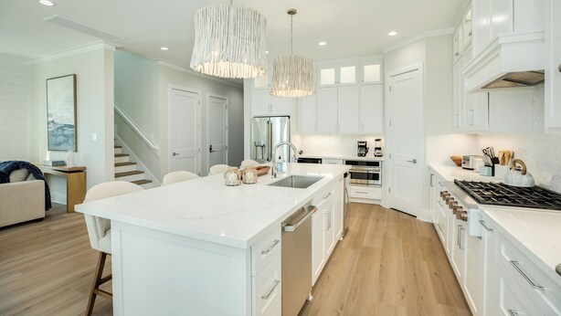 A modern kitchen with white cabinetry, a central island, stainless steel appliances, and pendant lighting. - Beautiful Second Row Beachside Home - Steps from Sand & Surf (Galveston)