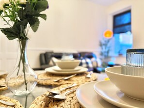A dining table with a vase of flowers, plates, and cutlery. - 2BR Apartment, Fast Wi-Fi, Apple TV & Netflix, 20 Off Long Stays (Newcastle upon Tyne)