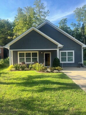 A residential house with a dark exterior, a front porch, and a well-maintained lawn. - Private 1-Bedroom Retreat (Charlotte)