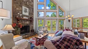 Ein geräumiges Wohnzimmer mit Kamin aus Stein, großen Fenstern und einer gemütlichen Sitzecke.