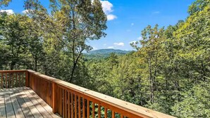 Eine Holzterrasse mit Blick auf einen Wald und Berge.