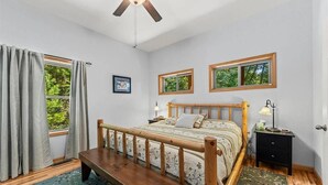 Ein Schlafzimmer mit einem hölzernen Bett, zwei Nachttischen, einer Bank und einem Deckenventilator.