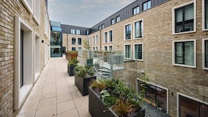 Un bâtiment moderne doté d’une façade en briques, de grandes fenêtres et d’une cour intérieure agrémentée de jardinières.