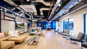 Un espace de bureau moderne doté d’une grande fenêtre, d’un mur d’accent bleu et d’un plancher en bois.