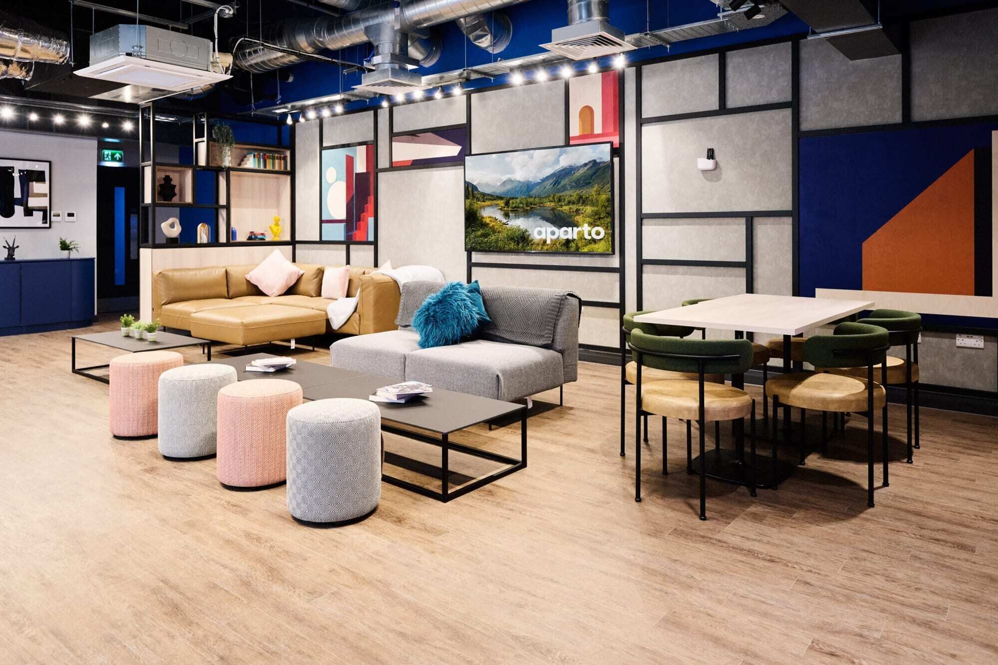 A modern lounge area with sofas, ottomans, and a dining table.