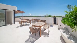 Eine Dachterrasse mit Sitzgelegenheiten im Freien, einem Glastür-Eingang und Blick auf die Stadtlandschaft.