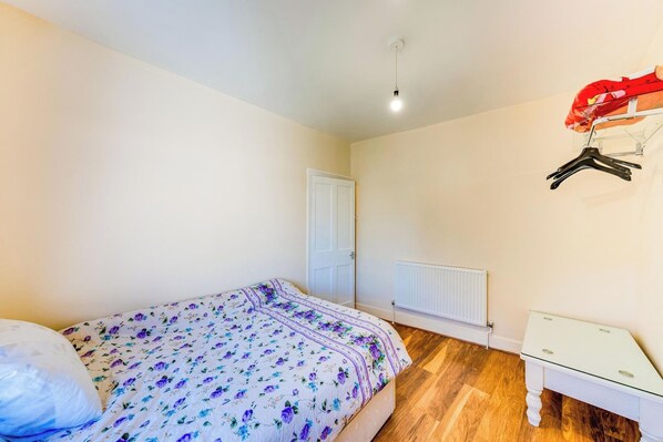 A bedroom with a bed, a white radiator, a white dresser, and a door. - 3 Bed House - Sleeps 6 - Garden - Central London (London)