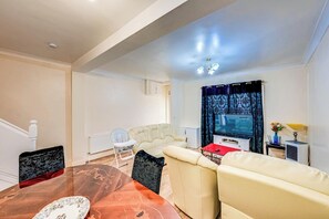 A living room with a sofa, a dining table, and a television. - 3 Bed House - Sleeps 6 - Garden - Central London (London)