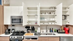 Eine moderne Küche mit weißen Schränken, einem Backofen, einer Mikrowelle, einem Gasherd und einem Spülbecken.