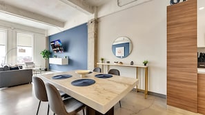 A modern dining area with a marble table, chairs, a TV mounted on the wall, and a minimalist decor. - Dallas Skyline View Flat w/ Pool, Gym & Free Parking (Dallas)