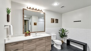 A modern bathroom with a large mirror, a sink, a toilet, and a bench. - Dallas Skyline View Flat w/ Pool, Gym & Free Parking (Dallas)