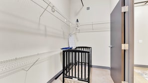 Una habitación con una cuna, un estante metálico y una puerta.