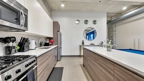 A modern kitchen with a stove, microwave, and coffee maker. - Dallas Skyline View Flat w/ Pool, Gym & Free Parking (Dallas)