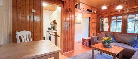 A wooden interior with a dining table, a sofa, and a coffee table.