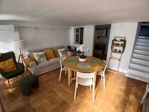 A living room with a sofa, a round wooden dining table with chairs, a small round ottoman, and a staircase leading to another level. - Beachfront home with spectacular ocean views (La Cala del Moral)