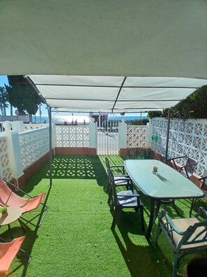 A patio with artificial grass, a table and chairs, and a white fence. - Beachfront home with spectacular ocean views (La Cala del Moral)