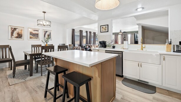Una cocina moderna con una isla central, armarios blancos y una lámpara colgante.
