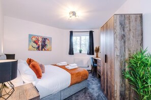 Ein modernes Schlafzimmer mit einem Bett, einem Schreibtisch und einem großen Fenster.