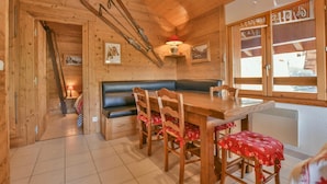 A wooden interior with a dining table, benches, and skis on the wall. - Cosy 6-person apartment in Chinaillon (Le Grand-Bornand)