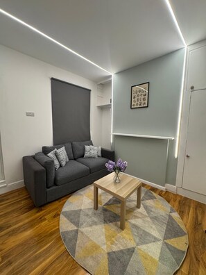 A modern living room with a grey sofa, a wooden coffee table, and a patterned rug. - Westfield London Apartments 2 (London)