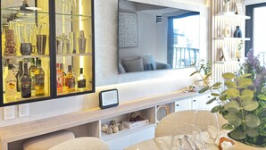 A modern living room with a large mirror, a glass cabinet with bottles, a sofa, and a view of the city. - Stylish 1BR w/Balcony near Larcomar in Miraflores (Miraflores)