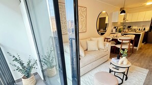 A modern living room with a sofa, ottoman, and a dining area with a table and chairs. - Stylish 1BR w/Balcony near Larcomar in Miraflores (Miraflores)