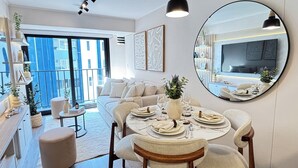A modern dining area with a round table set for four, a sofa, and a large mirror reflecting the room. - Stylish 1BR w/Balcony near Larcomar in Miraflores (Miraflores)
