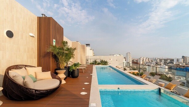 A rooftop pool area with a lounge chair, potted plants, and a view of the cityscape. - Stylish 1BR w/Balcony near Larcomar in Miraflores (Miraflores)
