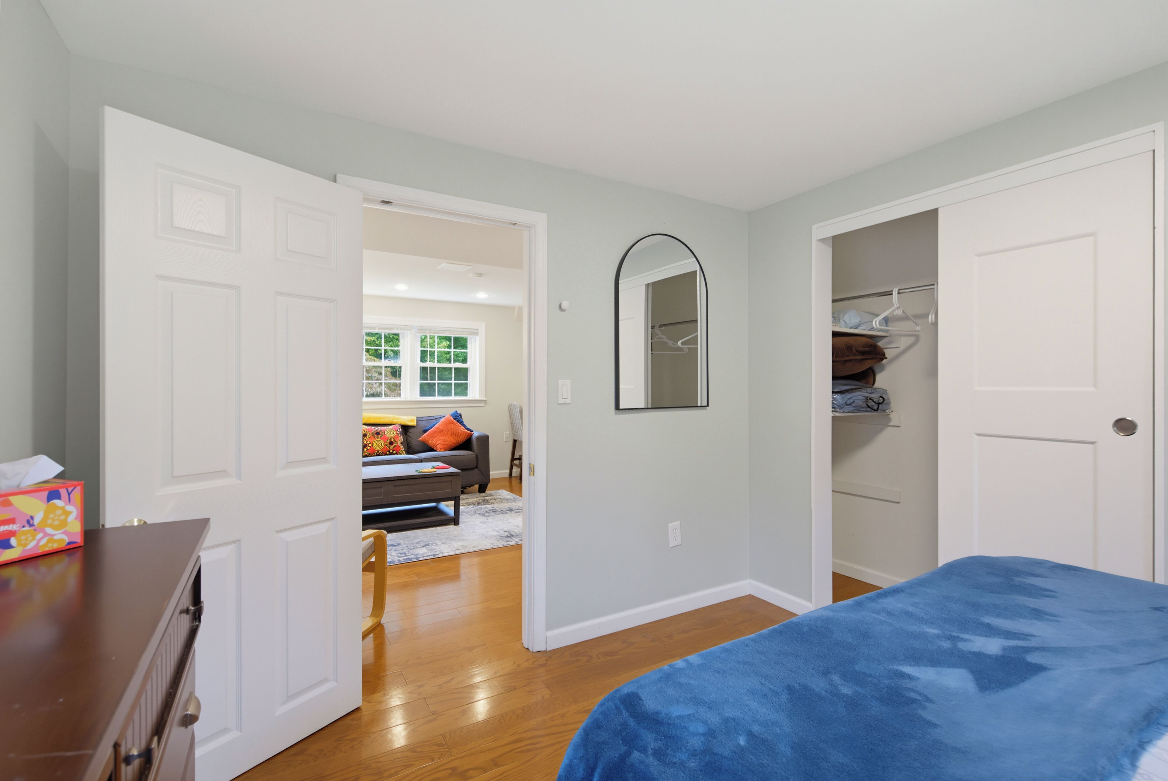 A bedroom with a bed, a dresser, a closet, and a door leading to another room.