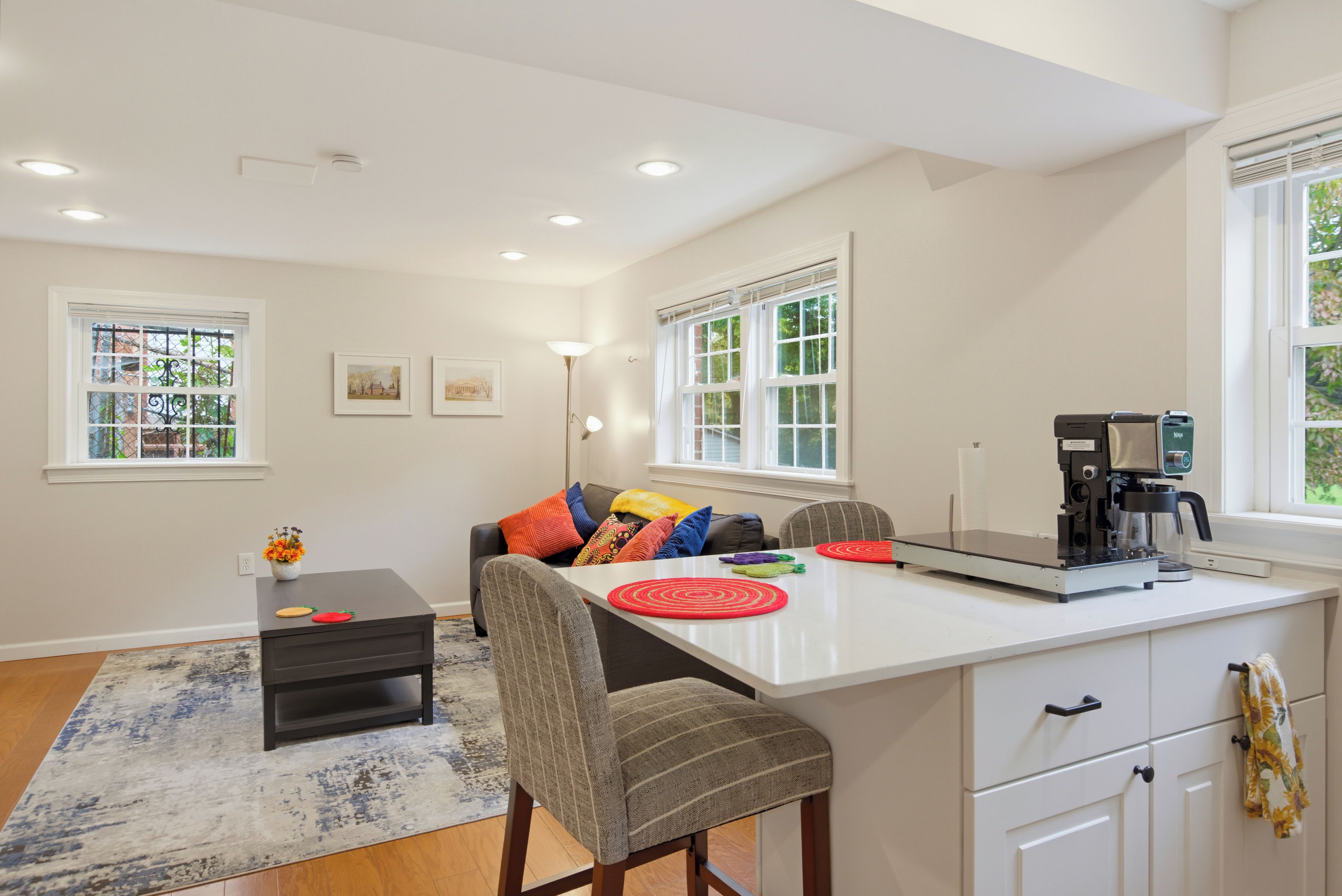 A modern kitchen with a central island, a coffee machine, and a dining area with a sofa and chairs.