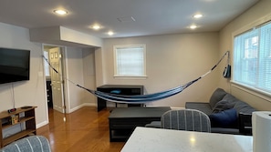 Una sala de estar con una hamaca, un televisor de pantalla plana, un sofá y una mesa de comedor.