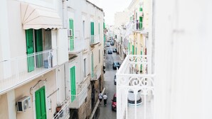 Un carrer estret amb edificis als costats, balcons i alguns cotxes aparcats.