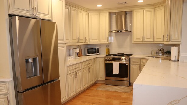 A modern kitchen with stainless steel appliances, white cabinetry, and a marble countertop. - A Great Place To Relax -A (Uniondale)